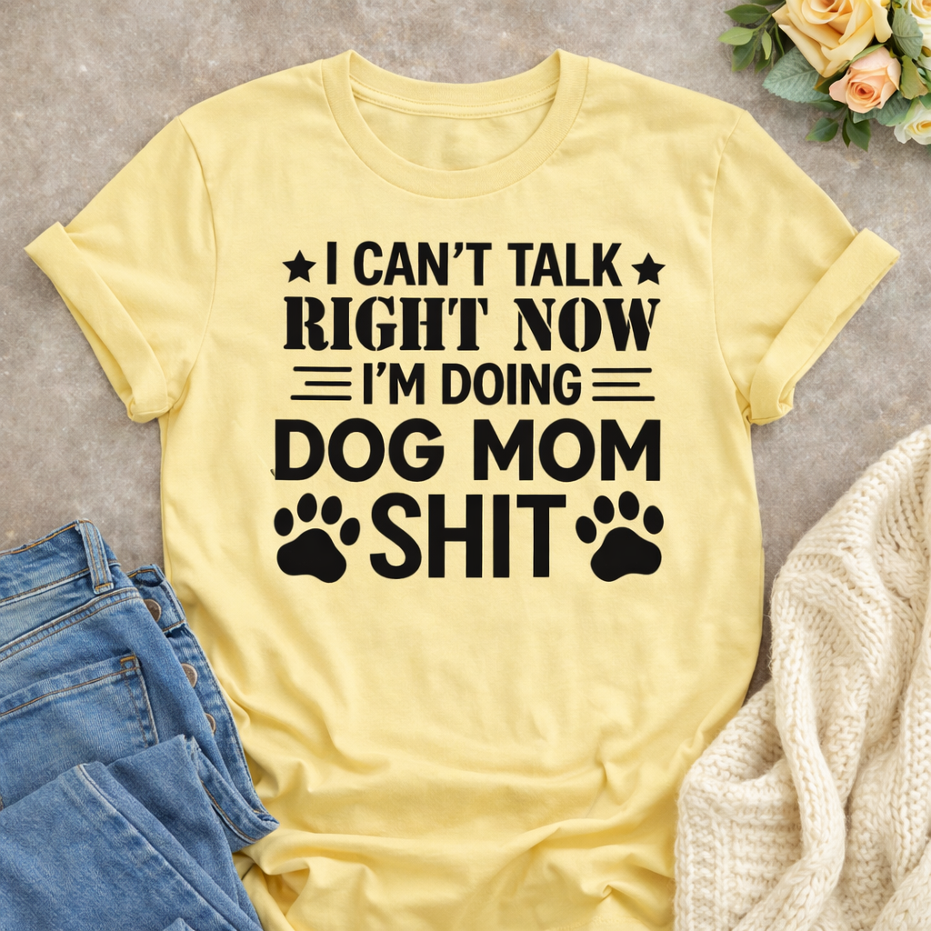 Yellow dog mom graphic T-shirt laid flat with bold humorous quote “I Can’t Talk Right Now I’m Doing Dog Mom Shit,” styled with denim jeans and a cozy knit cardigan