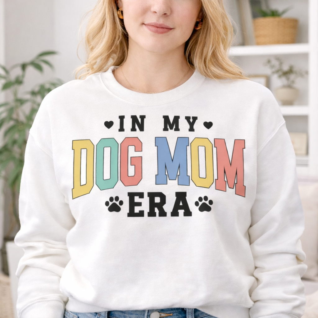 Woman wearing white sweatshirt with colorful In My Dog Mom Era SVG design featuring bold letters and paw prints
