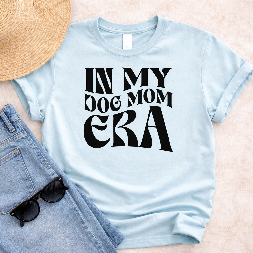Light blue t-shirt with In My Dog Mom Era SVG design in bold black lettering, styled with jeans, sunglasses and straw hat