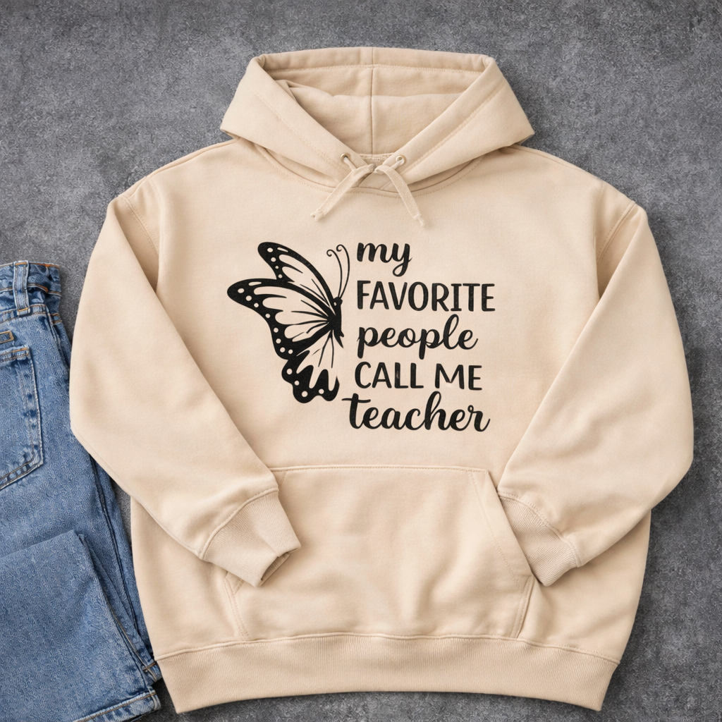 Beige hoodie with “My favorite people call me teacher” SVG design and butterfly graphic in black, flat lay with denim jeans on neutral background – Funny Teacher SVG Quotes