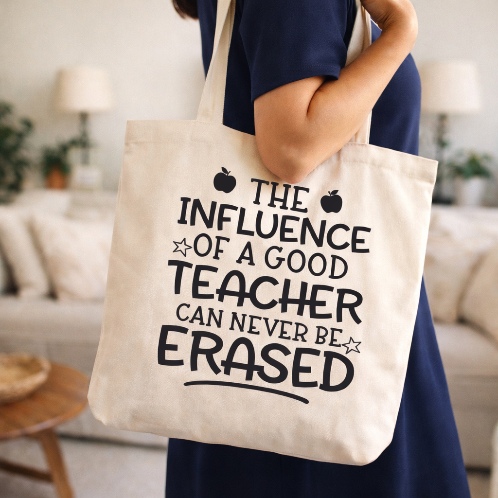 Beige tote bag with “The Influence of a Good Teacher Can Never Be Erased” SVG design in black, worn on shoulder in cozy indoor setting – Funny Teacher SVG Quotes