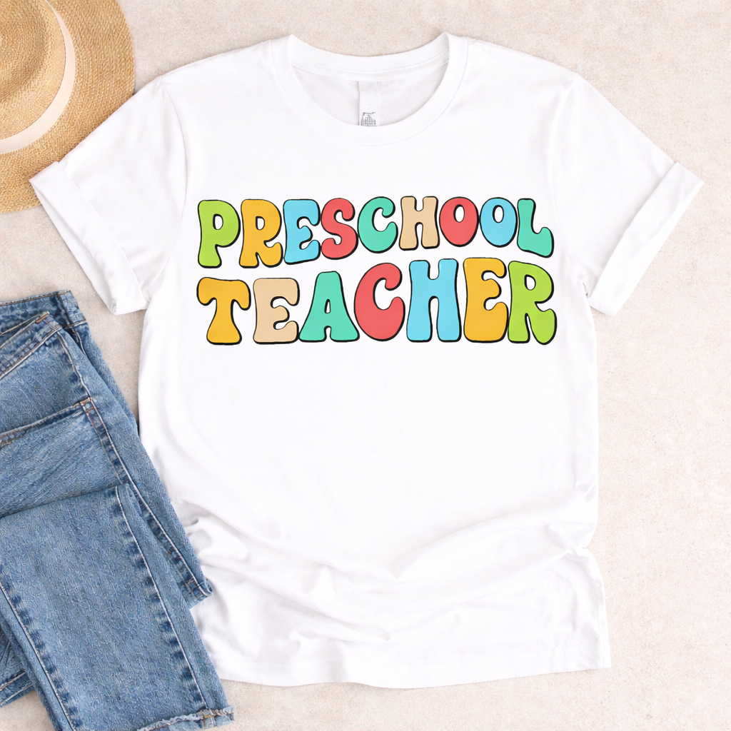 White t shirt flat lay with Preschool Teacher SVG in bright colorful letters styled with denim shorts and straw hat