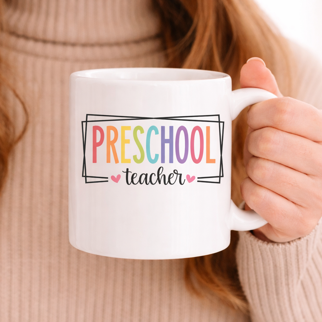White mug held in hand featuring Preschool Teacher SVG with colorful lettering and small heart accents in a cozy setting